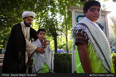 روحانی حاضر در اردوی دانش آموزان پیش از ورود پرویز فتاح، رئیس کمیته امداد امام خمینی (ره) چفیه های دانش آموزان را مرتب می کند.