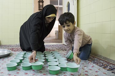 حسین به خواهرش فائزه مسعودی در آماده سازی ظروف کمک می‌کند