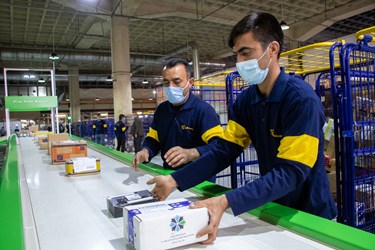کارکنان اداره کل پست استان فارس، بسته های پستی را روی دستگاه قرار می دهند.