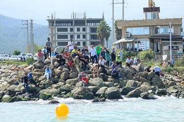 تماشاچيان بر روي اسكله سنگي ساحل كپورچال نوشهر از نزديك در حال مشاهده مسابقه هستند 