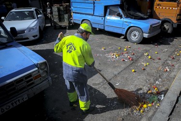 تمیز کردن میوه های زمین ریخته شده توسط کارگران شهرداری در میدان مرکزی میوه و تره بار تهران