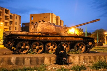 دختر جوان  در منطقه دوکوهه کنار تانک از کار افتاده از زمان جنگ دفاع مقدس  استراحت میکند
