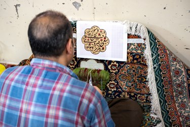 مردی  در حال رفو کردن یک فرش قدیمی است