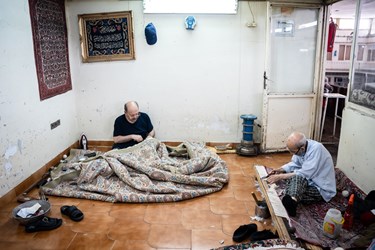 چند مرد در حال رفو کردن فرش هستند