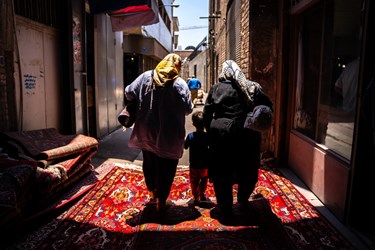 خانواده ای در حال خارج شدن از بازار فرش تهران هستند