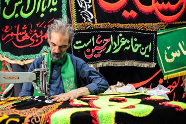 سید در حال دوخت پرچم محرم است