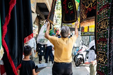 یک مرد در حال انتخاب پرچم در آستانه ی محرم است