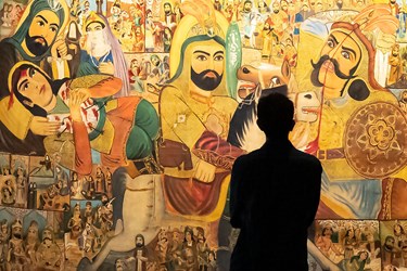 بازدید کننده‌‌ای که نقاشی واقعه عاشورا  را در نمایشگاه همچنان جاری