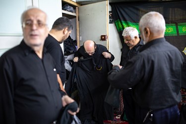 هیئتیان مشغول پوشیدن پیراهن سقایی هستند