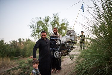 یکی از خادمین کمک میکند تا زائرین  وسایل خود را به کنار رود فرات منتقل کنند