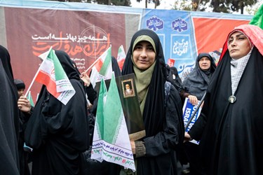 یک دختر نوجوان پرچم ایران را در راهپیمایی 13 آبان در دست دارد