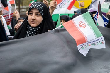 یک دختر نوجوان پرچم ایران را در راهپیمایی 13 آبان در دست دارد