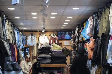 علاقمندان به فوتبال در یک بوتیک لباس فروشی مشغول تماشای فوتبال ایران و قطر هستند