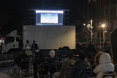 علاقمندان به فوتبال در میدان نبوت مشغول تماشای دیدار تیم‌های  ایران و قطر  هستند