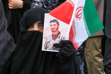 حضور بانویی کهنسال که عکس شهیدی را در دست گرفته است در خیابان امام رضا (ع)  مشهد در جشن 45 سالگی انقلاب 