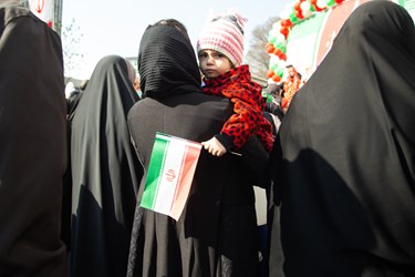 دختر خردسال در اغوش مادر که در راهپیمایی 22 بهمن 1402 شرکت کرده است.