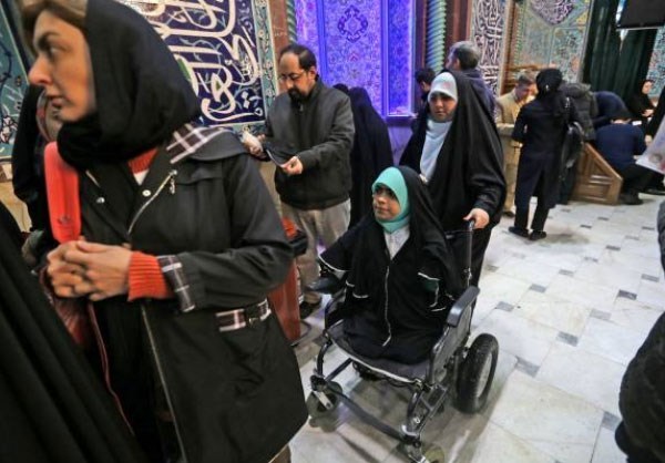 A handicapped woman makes her way to the voting booth in Tehran