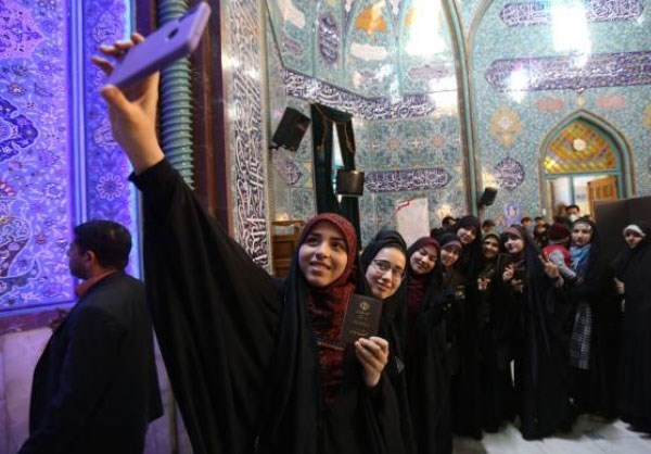 Young women pose for a “selfie” before casting their votes